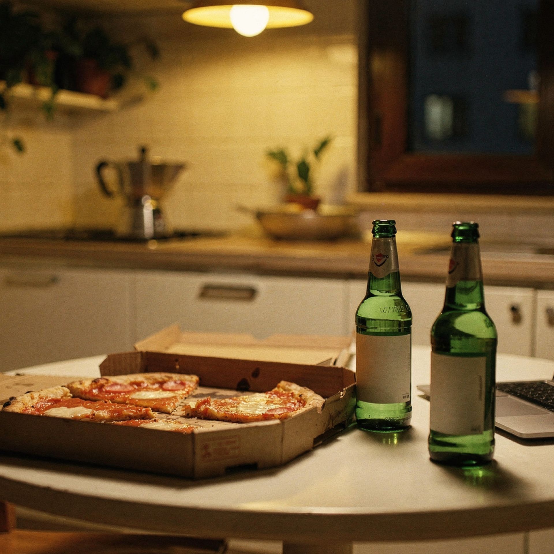 Tavolo cucina con due birre, pizza margherita e laptop, appartamento studenti via Padova Milano