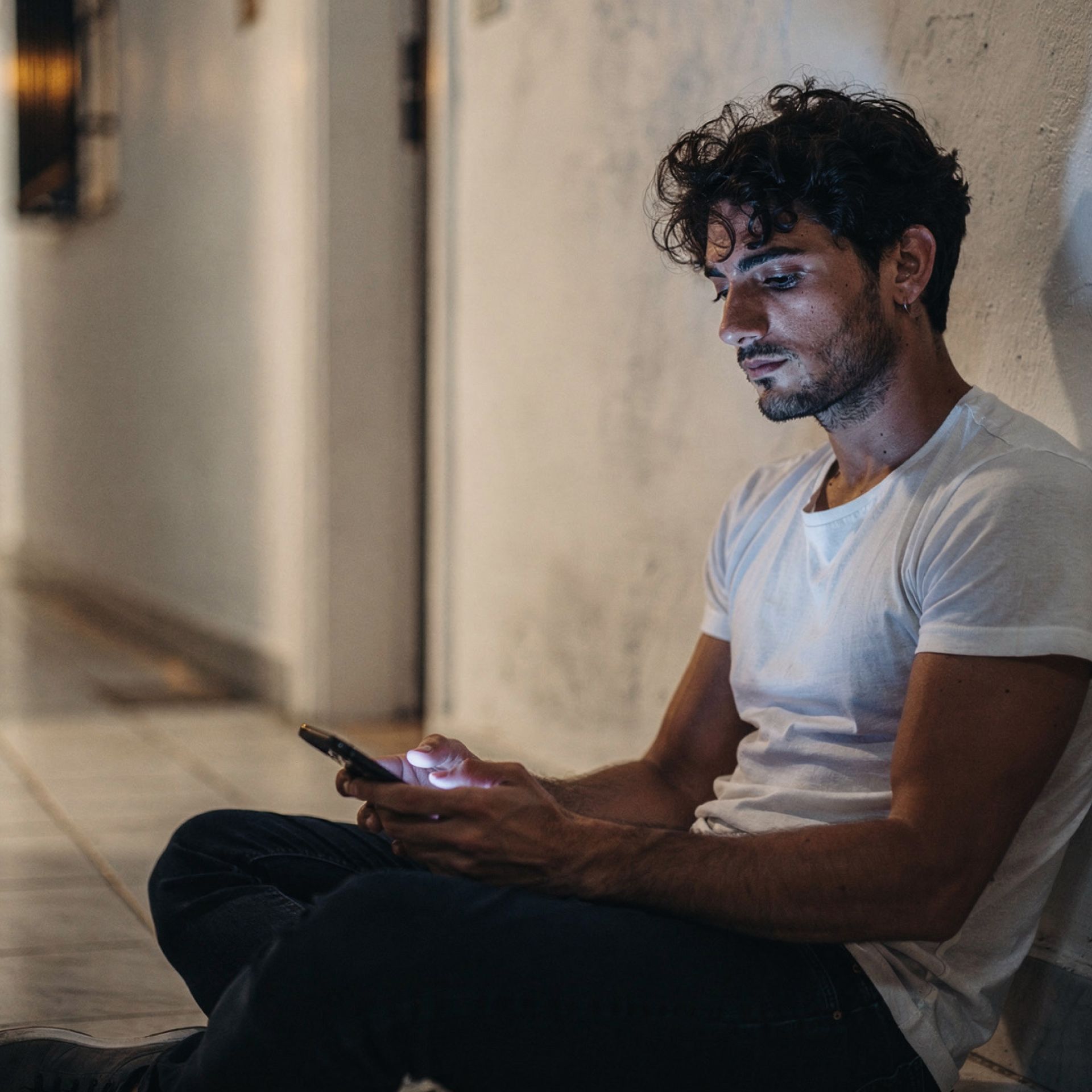 Racconti gay coming out: un giovane uomo al telefono di notte, seduto in corridoio